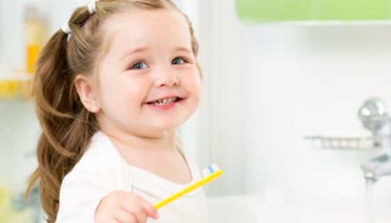 21965611 - smiling child girl brushing teeth in bathroom